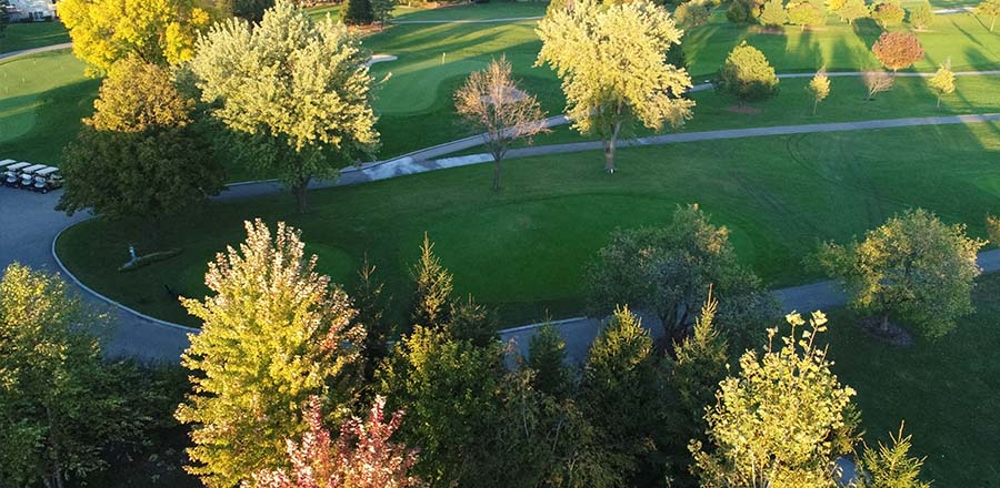 image of aerial view of golf course green with sun casting shadows over the trail